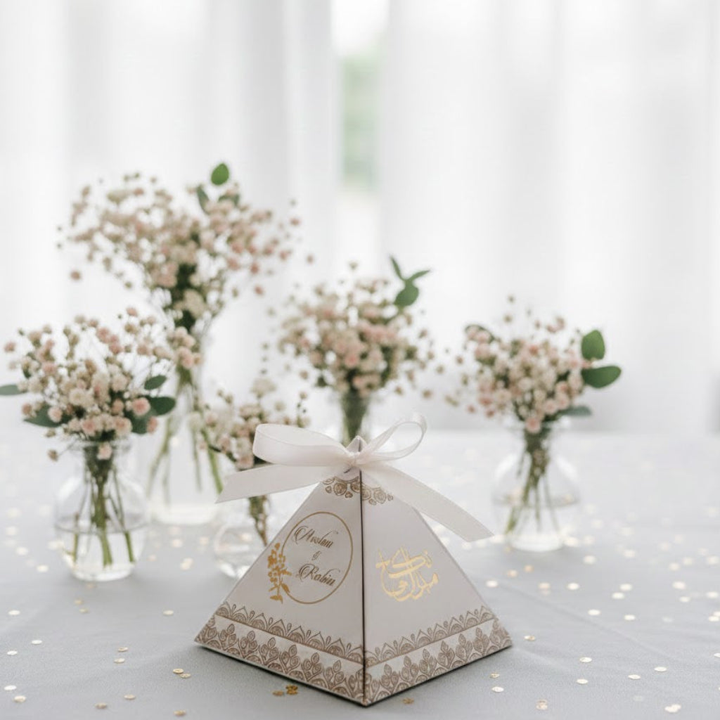 Pyramid-shaped favour box with decorative elements on a light background with flowers.
