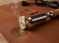 Gold leather stamp on a brown leather surface with smoke rising from it.