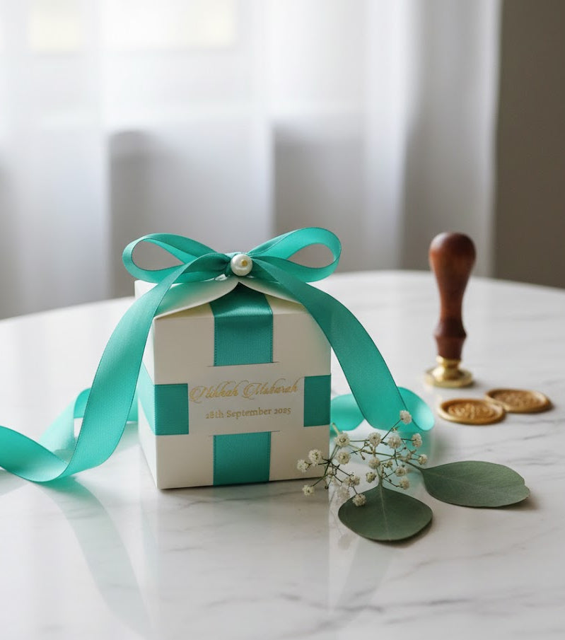 bid box with teal ribbon and decorative elements on a marble surface