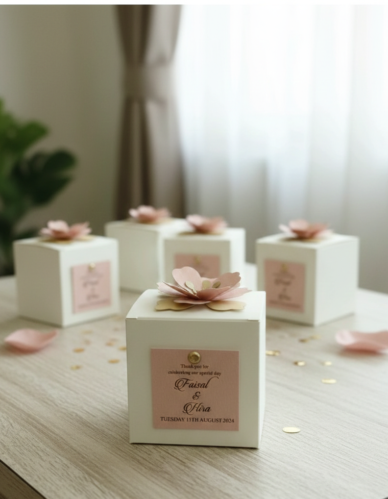 White bid boxes with pink floral decorations on a wooden surface.