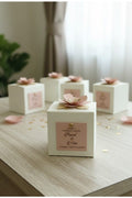 White gift boxes with pink floral decorations on a wooden surface