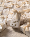 White bid boxes with gold text and ribbons on a textured surface
