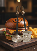 Burger with decorative skewers on a wooden board with fries and ketchup.