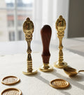 Decorative wax seals with gold and wooden handles on a textured surface.