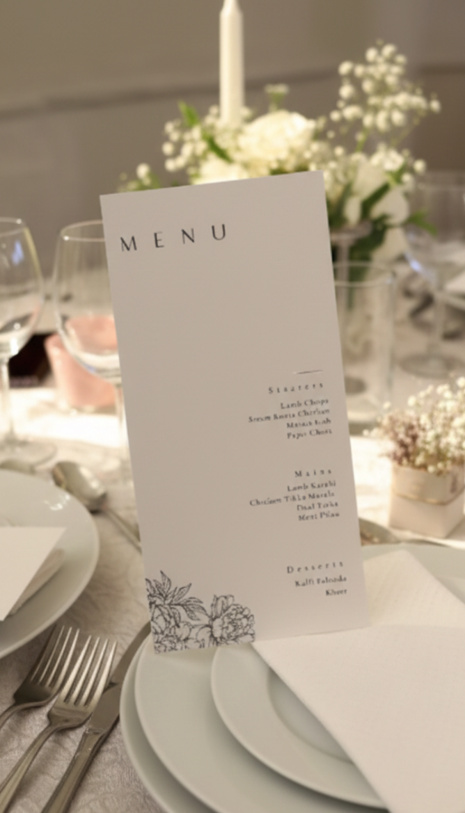 Menu card on a table setting with plates, cutlery, and floral centerpieces.