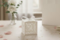 White decorative bid box with a ribbon on a table with flowers in the background
