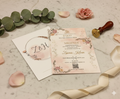 Floral wedding invitation with RSVP card on a marble surface with decorative elements.