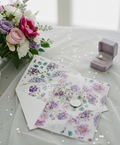 Floral stationery set with cards and envelopes on a table with flowers and jewelry box.