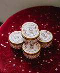 Decorative tins with floral designs on a red textured surface