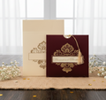 velvet  wedding invitation card with gold intricate design on a wooden surface with white flowers.