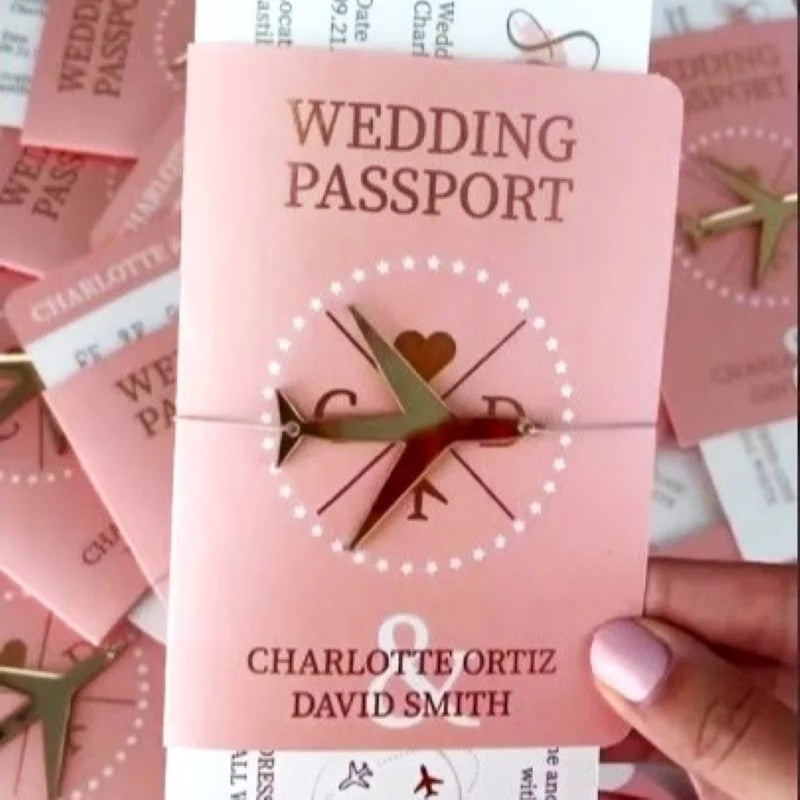 Pink 'Wedding Passport' with airplane and heart design held by a hand.