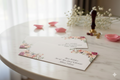 Floral weddingenvelope for meney on a wooden table with decorative items.